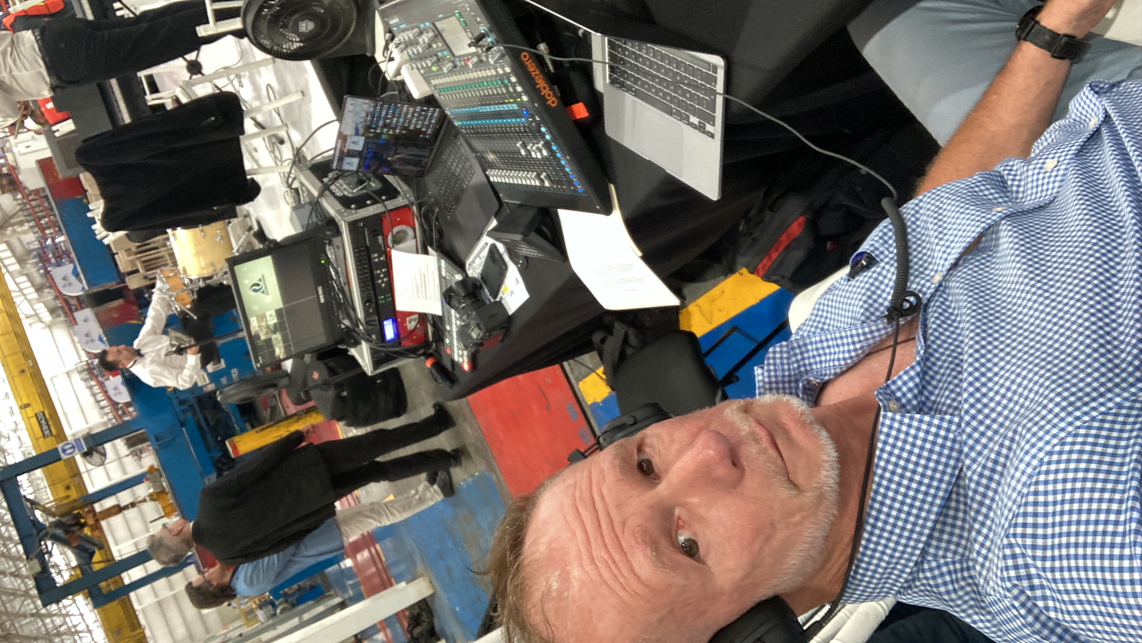 Simultaneous interpreter at live audio mixing console on manufacturing plant floor