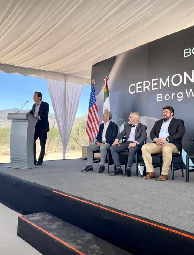 Binational corporate ceremony with U.S. and Mexico flags, interpreted executive remarks