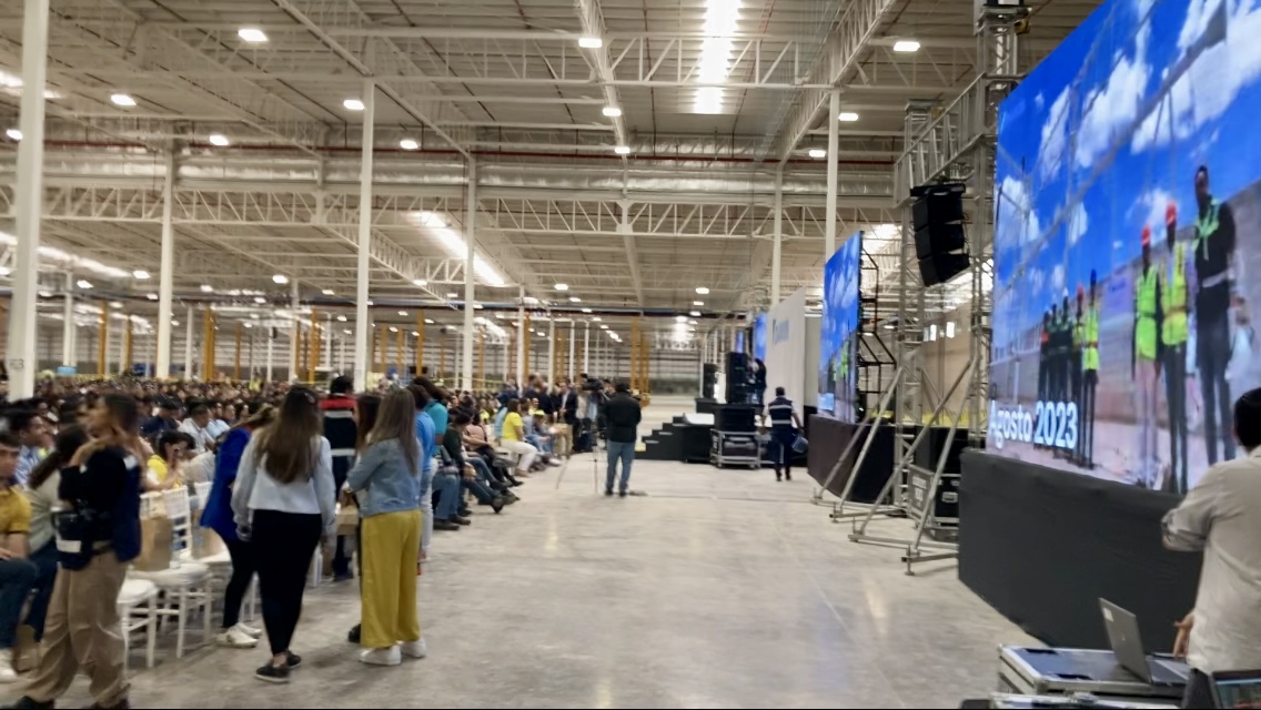 Large audience at manufacturing facility event with live interpretation support